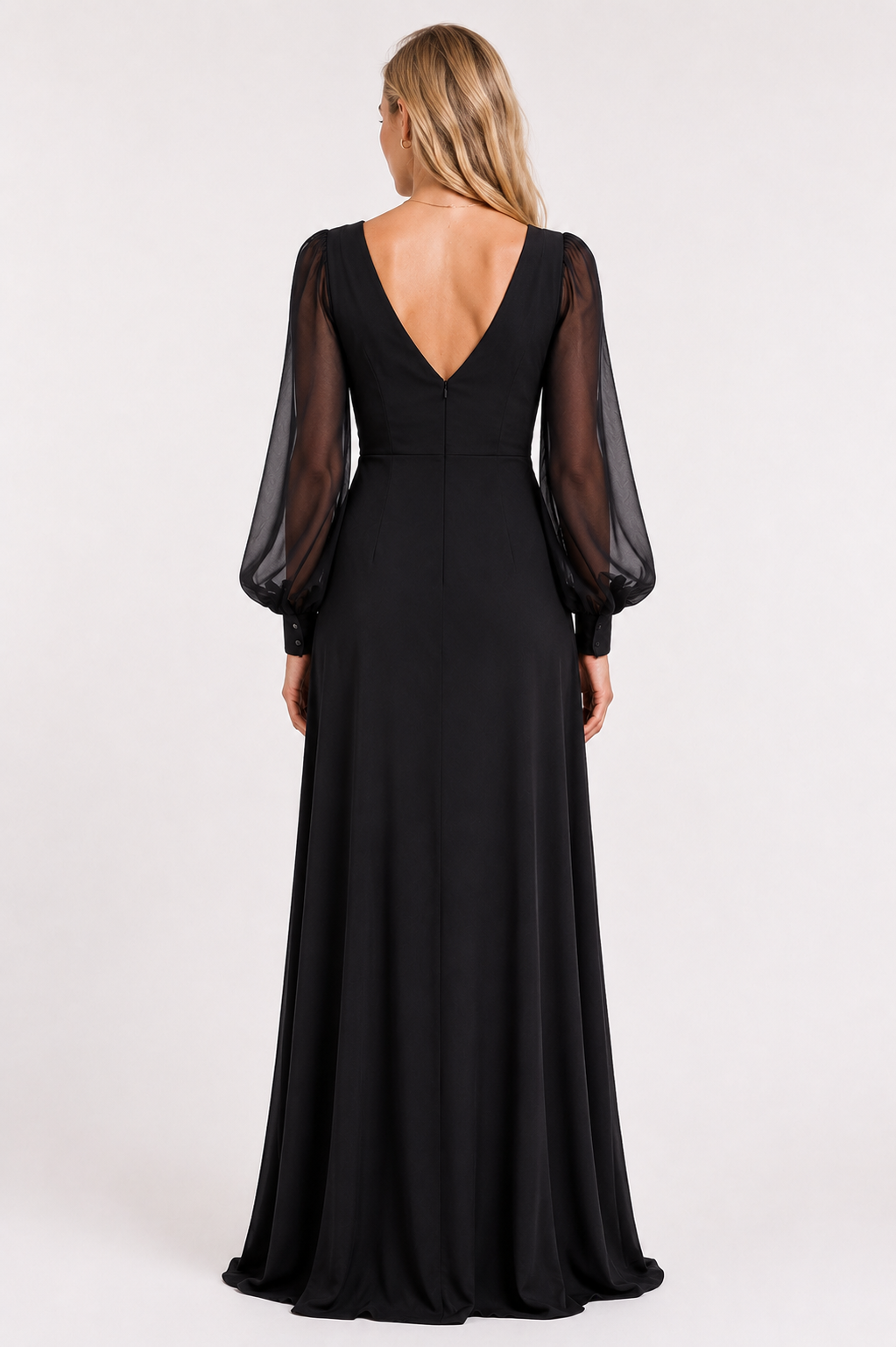 A woman viewed from the back wearing a floor-length black gown with sheer long balloon sleeves and a deep V back, photographed against a plain light studio background.