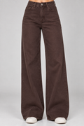 A person wearing dark brown wide-leg jeans with white sneakers, shown from the waist down against a light gray studio background.