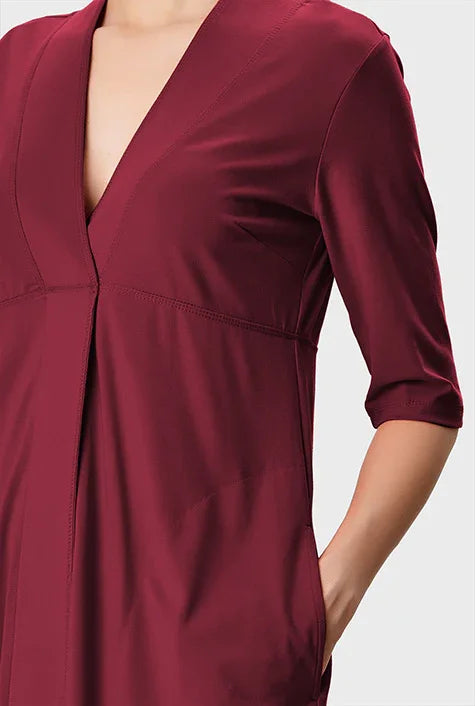 Cotton jersey empire A-line dress with deep V-neck, casual midi length, by nams-ropa, shown on a hanger against a white background.