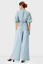 Light wash cotton denim palazzo jumpsuit with zip front and belt, featuring wide-leg design and comfortable one-piece style.
