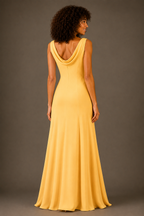 A woman shown from the back wearing a sleeveless, floor-length yellow gown with a draped neckline and a fitted silhouette, photographed against a plain taupe-gray studio background.