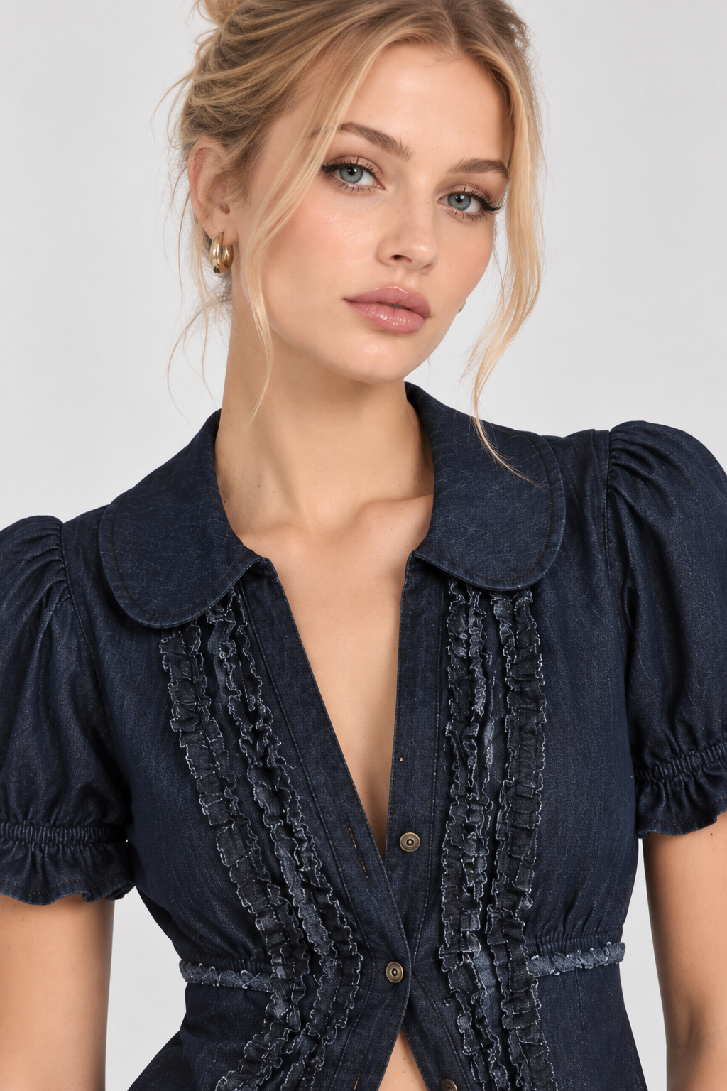 A close-up of a woman wearing a dark navy blue blouse with puff sleeves, a Peter Pan collar, and ruffled trim details on the front.