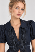 A close-up of a woman wearing a dark navy blue blouse with puff sleeves, a Peter Pan collar, and ruffled trim details on the front.