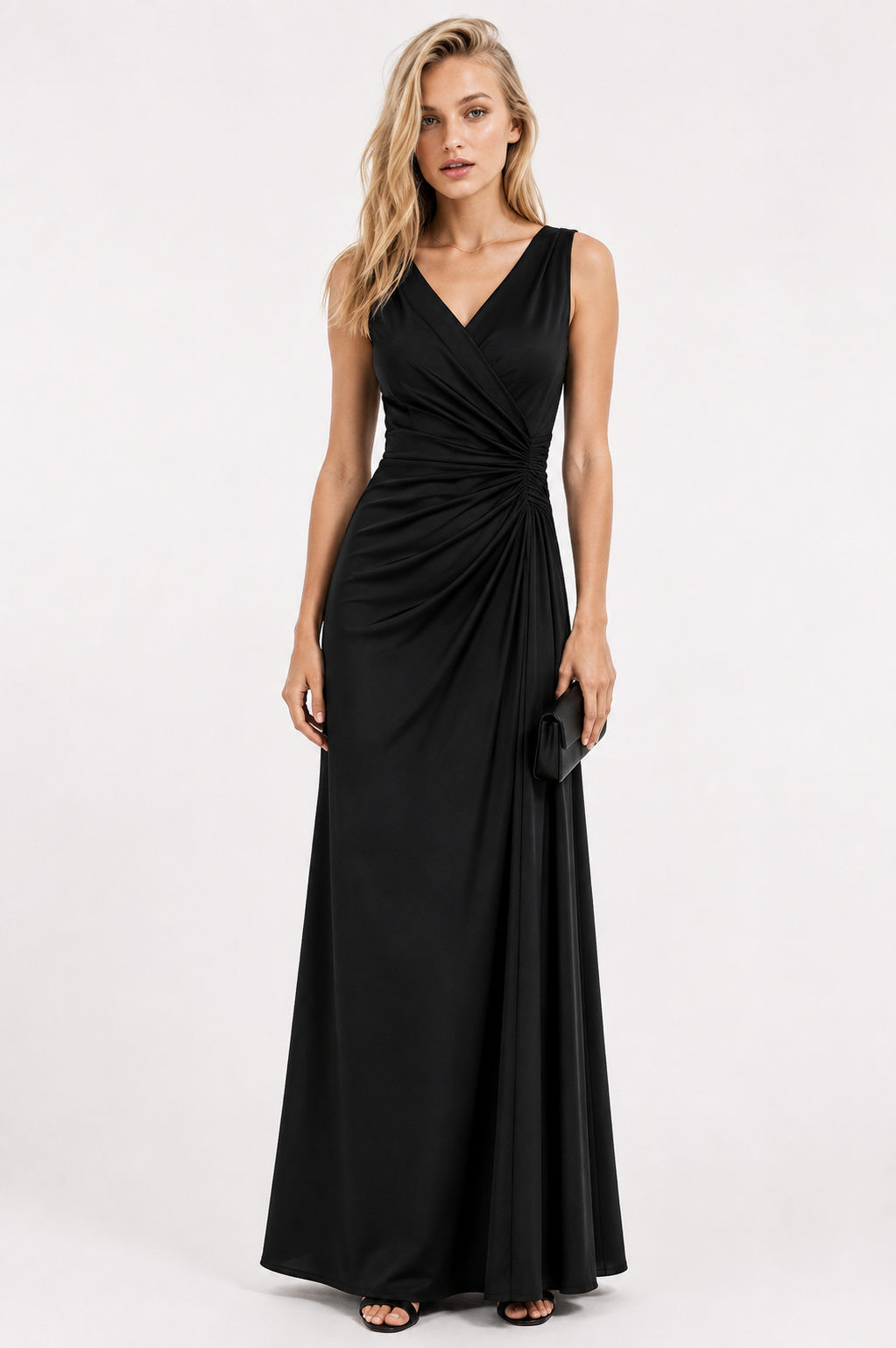 A woman modeling a sleeveless black maxi dress with a V-neckline and draped wrap-style bodice, standing against a plain light gray studio background.