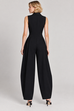 A woman modeling a black sleeveless high-neck wide-leg jumpsuit from the back, shown against a plain light gray studio background.
